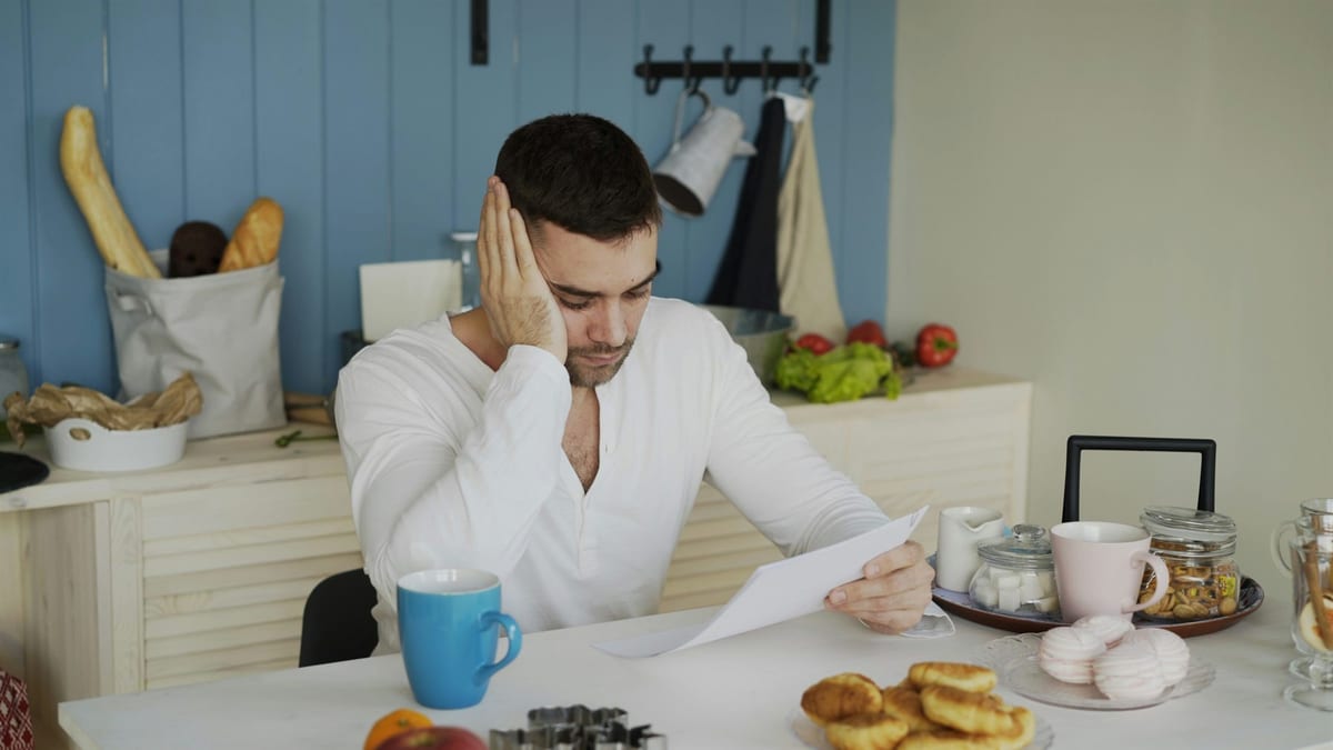 Man sitting overwhelmed at a table in his kitchen