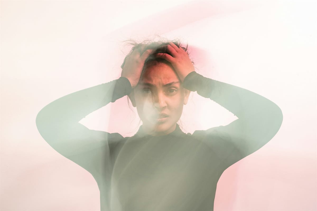 Double-exposure portrait of a distressed person holding their head