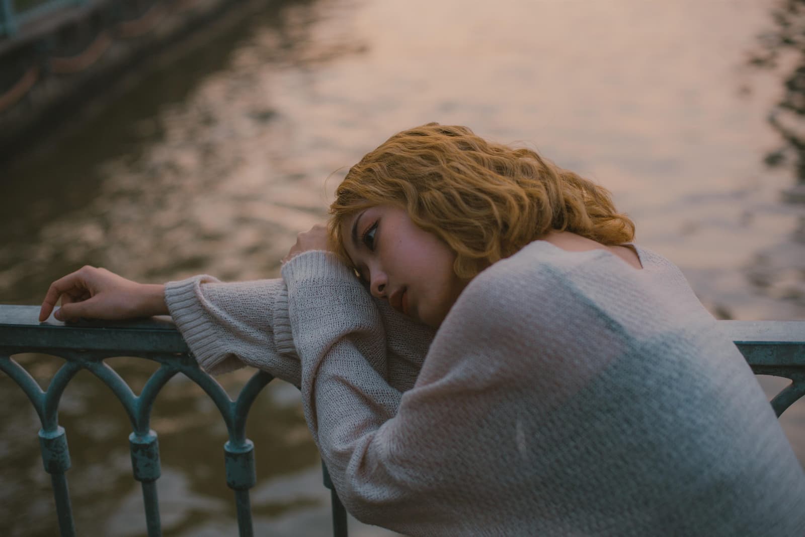Woman sitting alone by the water while experiencing emotional distress