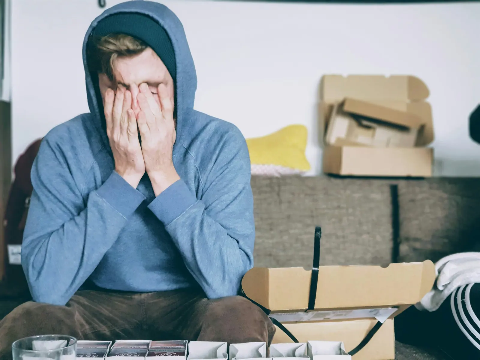 Overwhelmed person sitting at home with their face in their hands