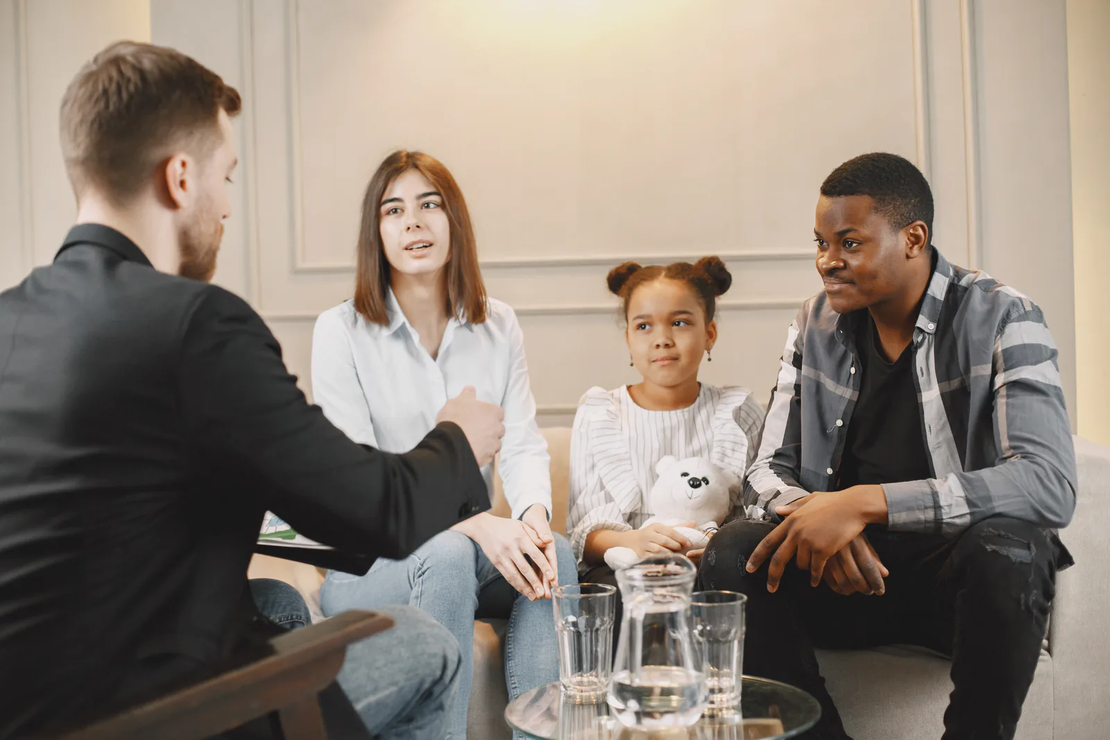 Family sitting together on a sofa talking with a counselor