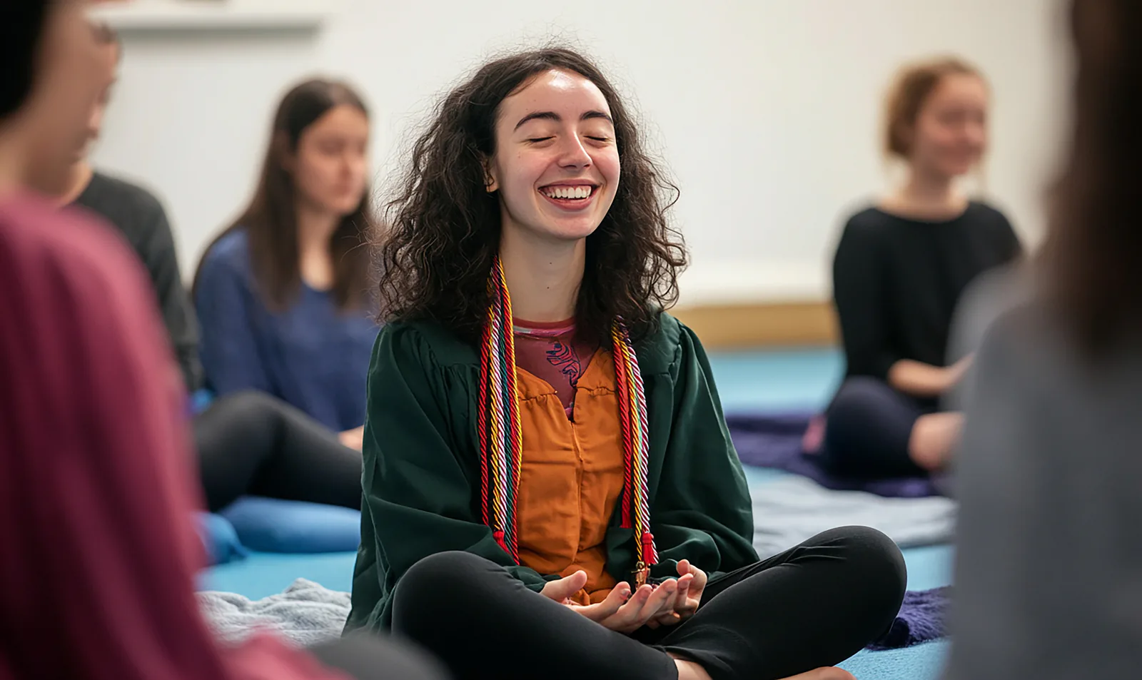 Person sitting cross-legged in a group session, smiling with eyes closed