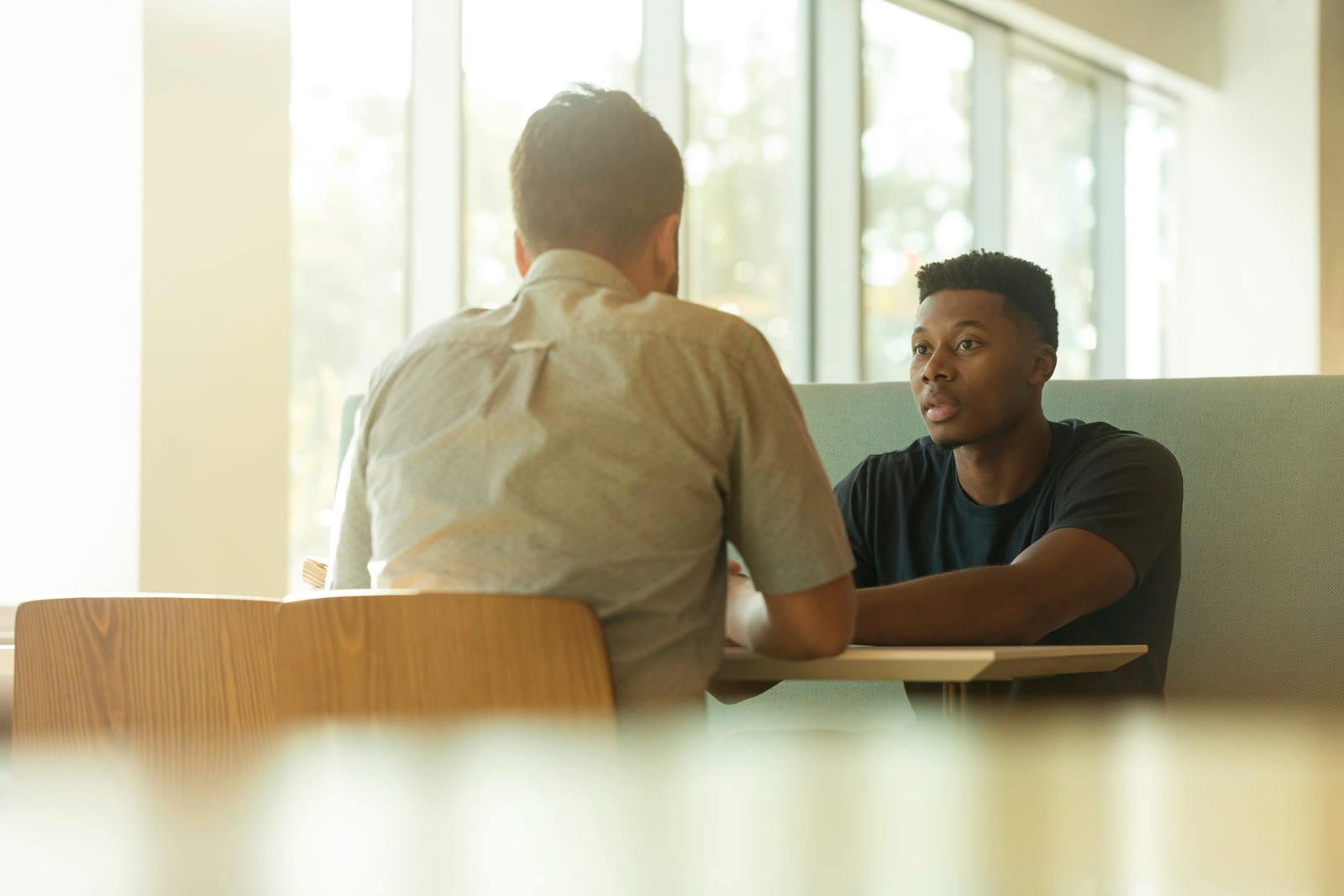 Two people talking across a table in a bright, calm consultation space